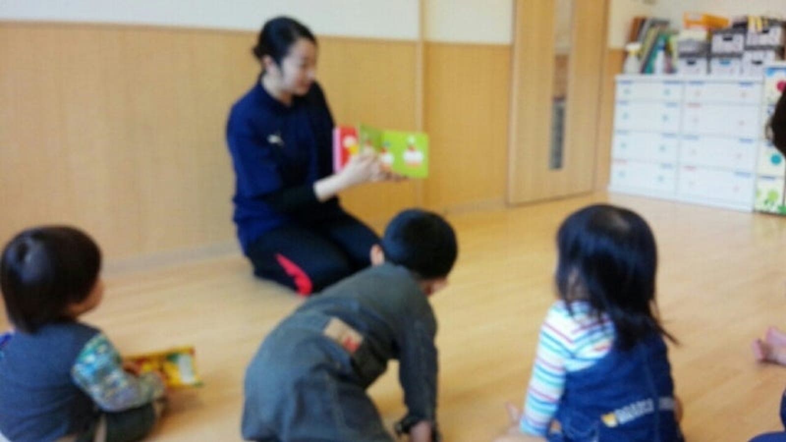 読み聞かせをするスタッフと子どもたちの後ろ姿