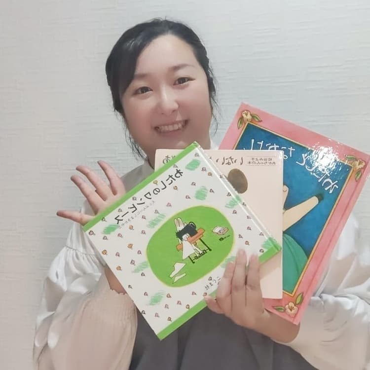 絵本を手に微笑む代表 川添聖華
